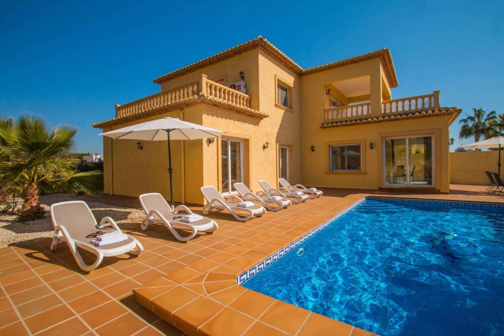 Villa con piscina con sillas y casa en Villa Tiago - PlusHolidays en Calpe