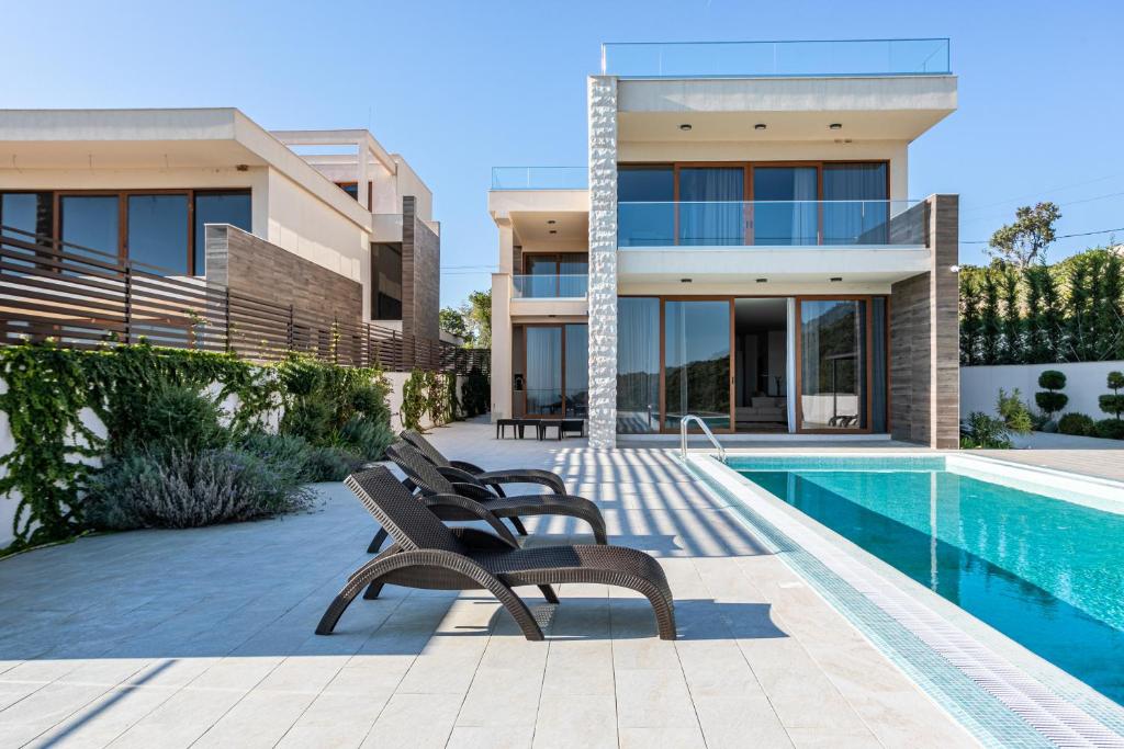 a villa with a swimming pool in front of a house at Cape Montenegro Villas in Krimovice