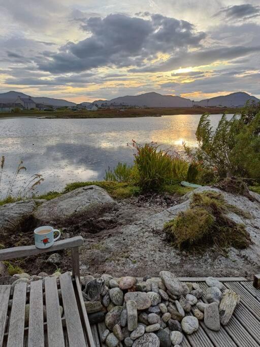 a cup of coffee sitting on a bench next to a lake at Hillview in Daliburgh