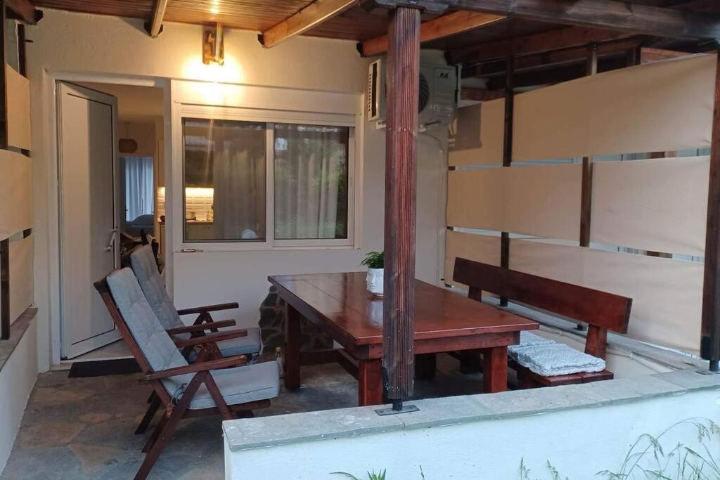 a patio with a wooden table and a bench at Holiday House near Beach in Skála Foúrkas