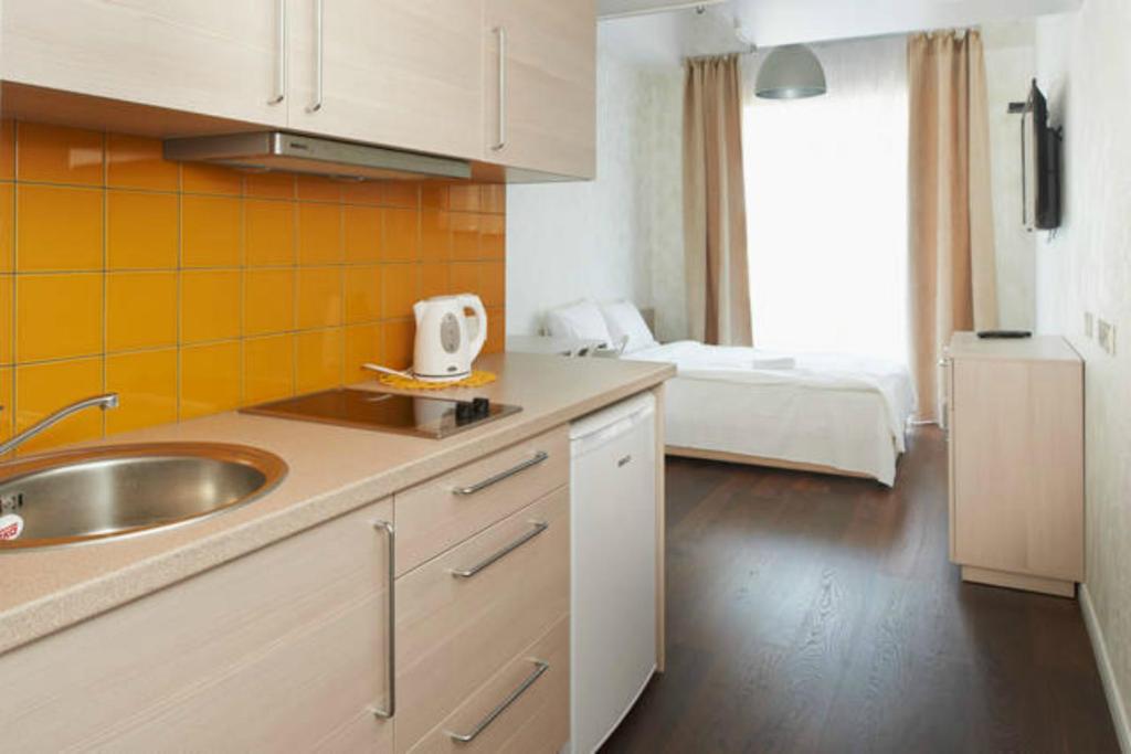 uma cozinha com um lavatório e um quarto com uma cama em Natalex MicroLofts em Vilnius