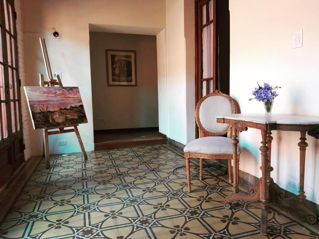 una habitación con una pintura, una mesa y sillas en La Escondida, Casa de Huéspedes en San Antonio de Areco