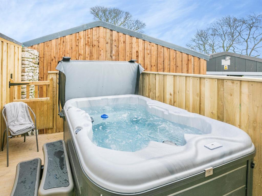 bañera de hidromasaje en una terraza con una valla de madera en Heathcote Hayloft - Uk36663 en Hartington