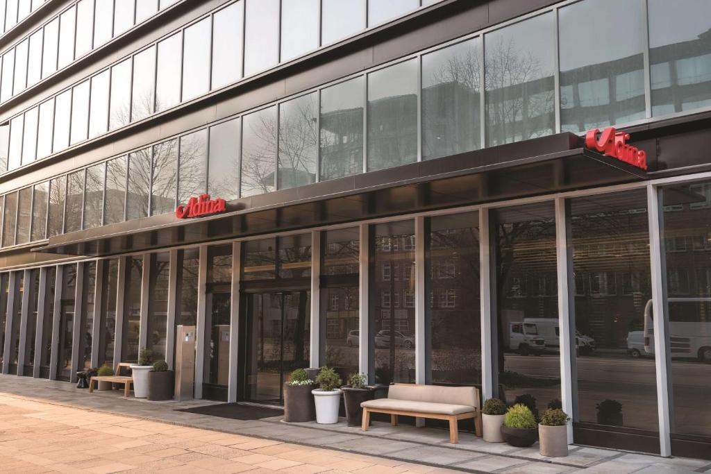 a large glass building with benches in front of it at Adina Apartment Hotel Hamburg Speicherstadt in Hamburg