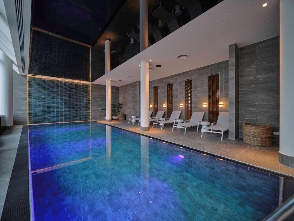 a swimming pool in a hotel with white chairs at Adina Apartment Hotel Vienna Belvedere in Vienna