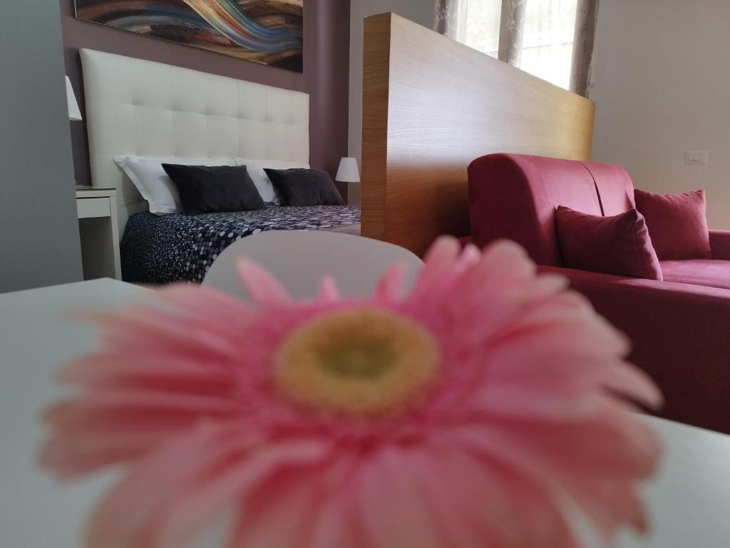 un fiore rosa in una stanza con letto di Casa Nicole a Castelbuono