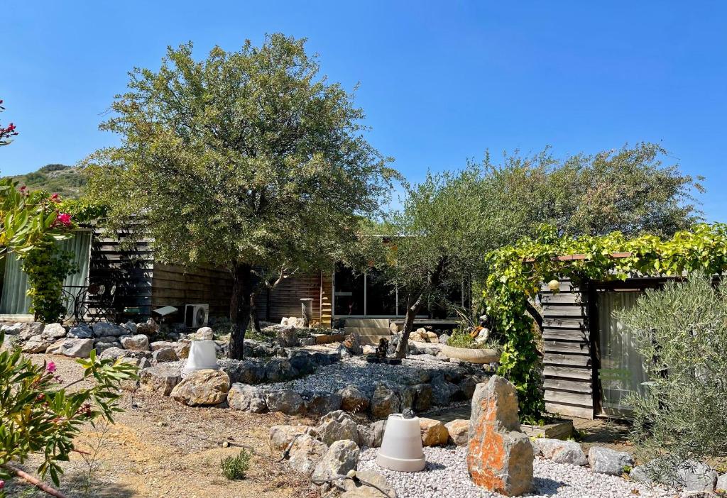 un giardino con rocce e alberi e un edificio di Gîte Les logis du Pech a Narbonne