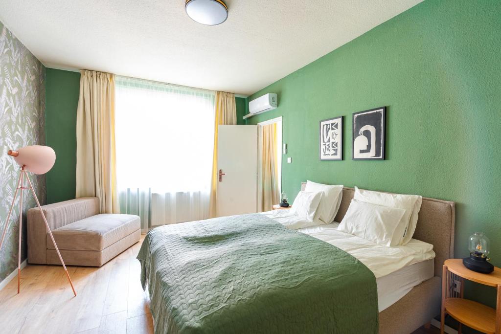 een groene slaapkamer met een bed en een stoel bij Sunny new luxurious home at the Jewish district in Boedapest