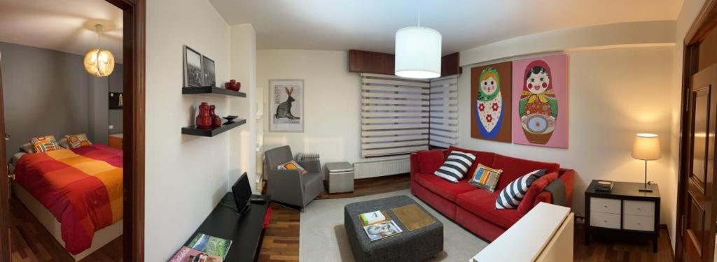 a living room with a red couch and a bed at Apartamento zona Ria do Burgo in A Coruña