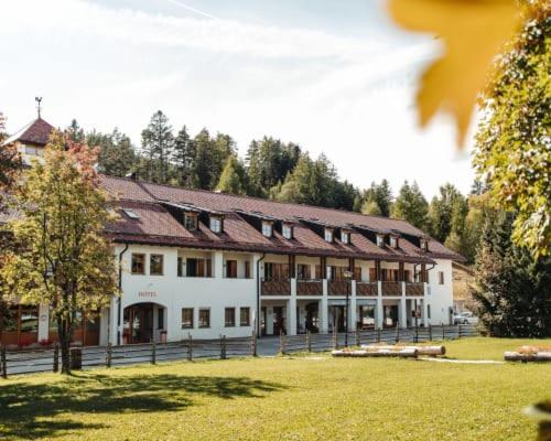 un grande edificio in un campo con alberi sullo sfondo di Hotel Corno Bianco a Nova Ponente
