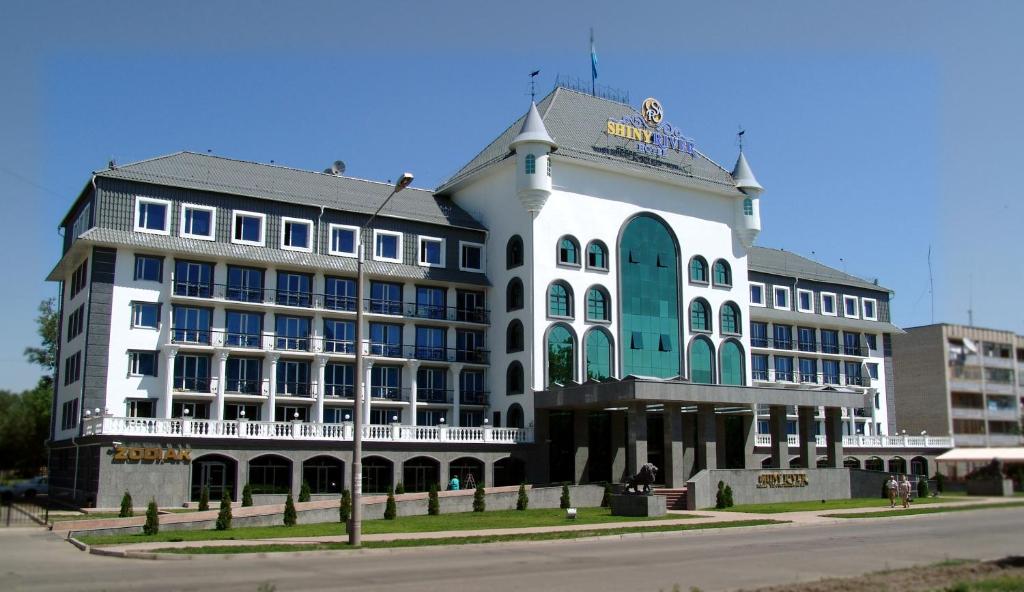 um grande edifício branco na esquina de uma rua em Shiny River Hotel em Ustʼ-Kamenogorsk
