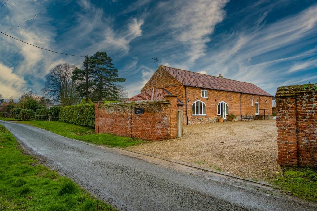 a brick house on the side of a road at Chestnut Barn, North Norfolk with private hot tub & close to beaches in Norwich