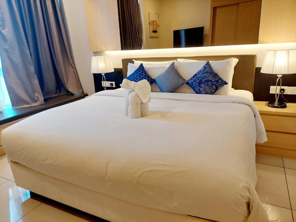 Un dormitorio con una gran cama blanca con una toalla. en Genting @ The MOST by NextGen, en Genting Highlands