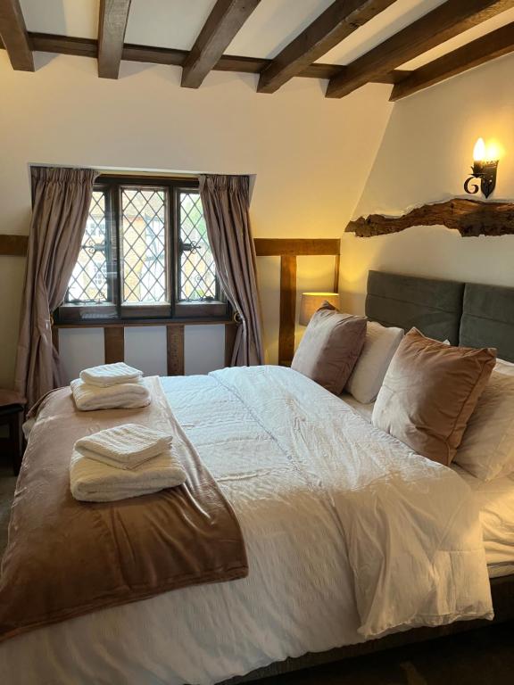 a bedroom with a large bed with two towels on it at The Smithy Cottage in Chilham