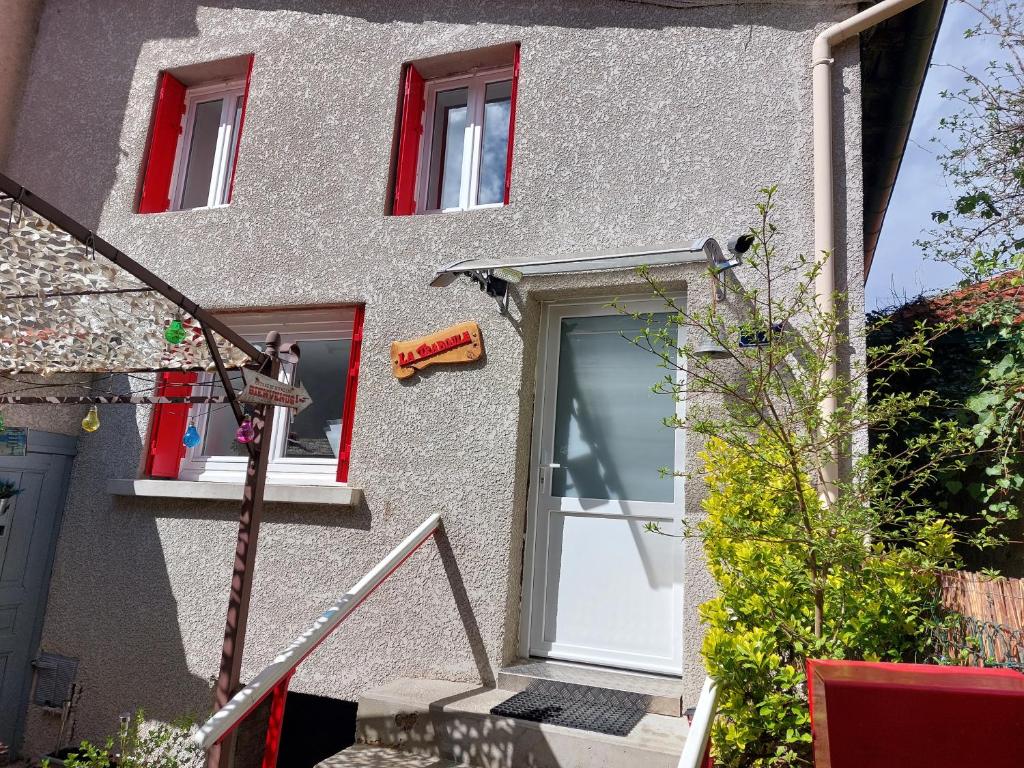 un edificio con una puerta blanca y ventanas rojas en LA TRABOULE Maison de ville avec extérieur, en Aurec-sur-Loire