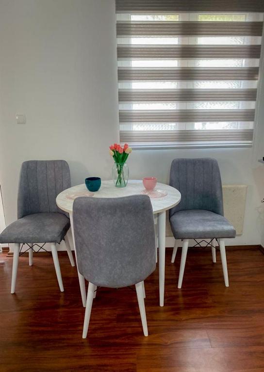 - une table avec trois chaises et un vase de fleurs dans l&#39;établissement Apartman Sanjar Vidikovac, à Kneževac