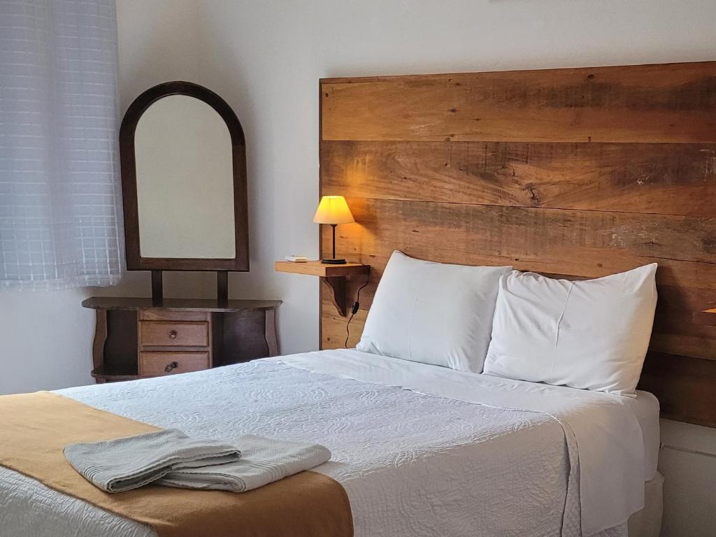 a bedroom with a large bed and a mirror at Pouso Mariazinha in Tiradentes