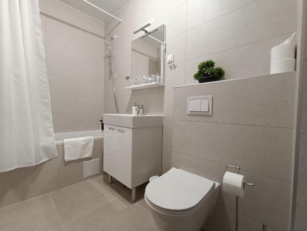 a white bathroom with a toilet and a sink at Apartman LEO in Velika Gorica