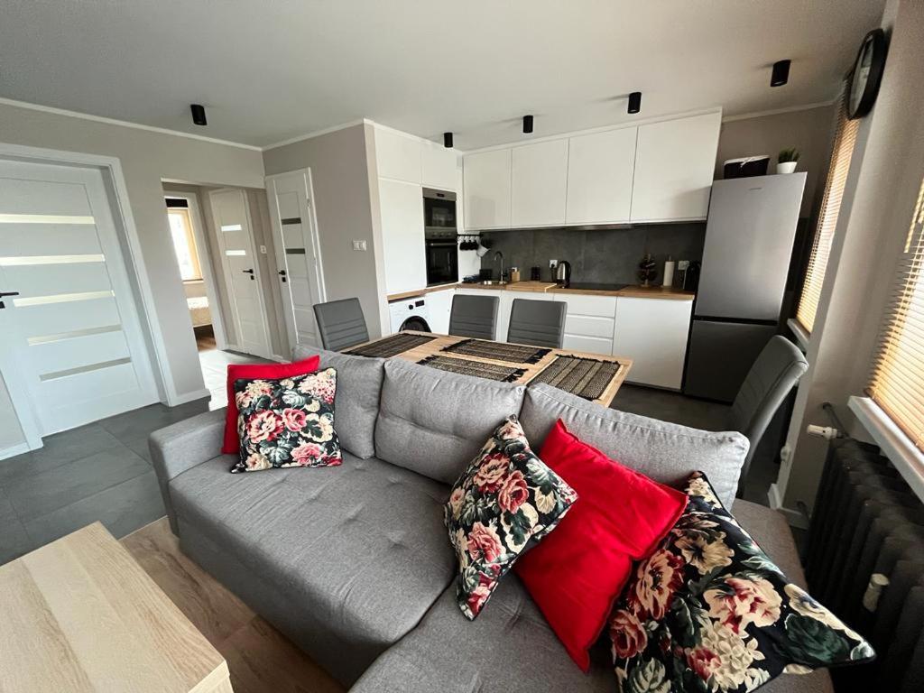 uma sala de estar com um sofá cinzento e almofadas vermelhas em Apartament Błękitna em Gdynia