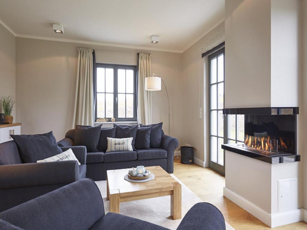 ein Wohnzimmer mit blauen Sofas und einem Kamin in der Unterkunft Reetland am Meer - Ihre Superior Reetdachvilla E28 - Zwei Schlafzimmer, Kamin & pure Wohlfühlatmosphäre in Dranske