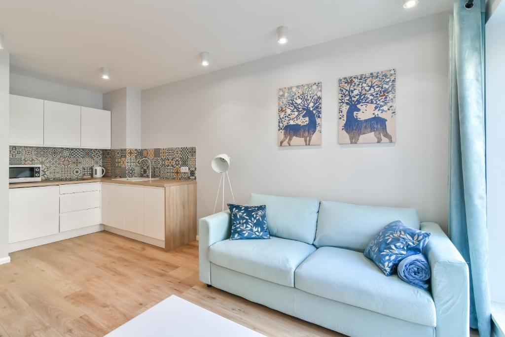 ein Wohnzimmer mit einem blauen Sofa und einer Küche in der Unterkunft LTC - Apartments Art Deco Śródmieście in Gdynia