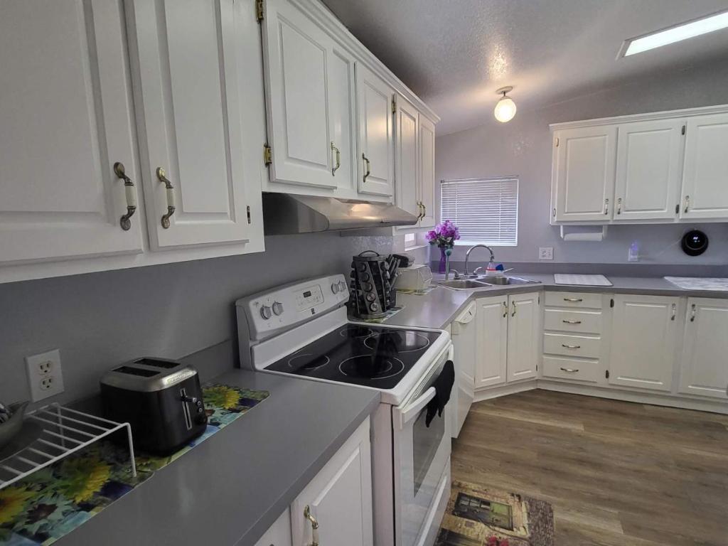 a kitchen with white cabinets and a stove top oven at Sun Angel House #1 Pahrump in Pahrump