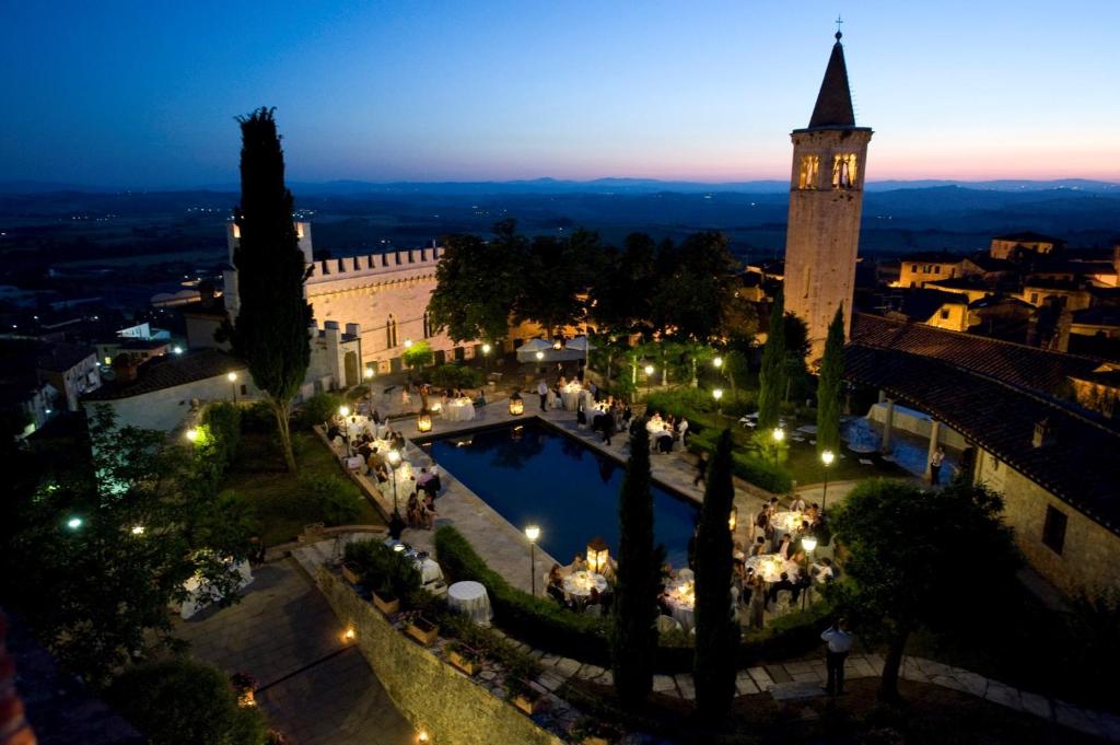 uma vista para uma cidade à noite com uma torre do relógio em Castello Delle Serre em Rapolano Terme