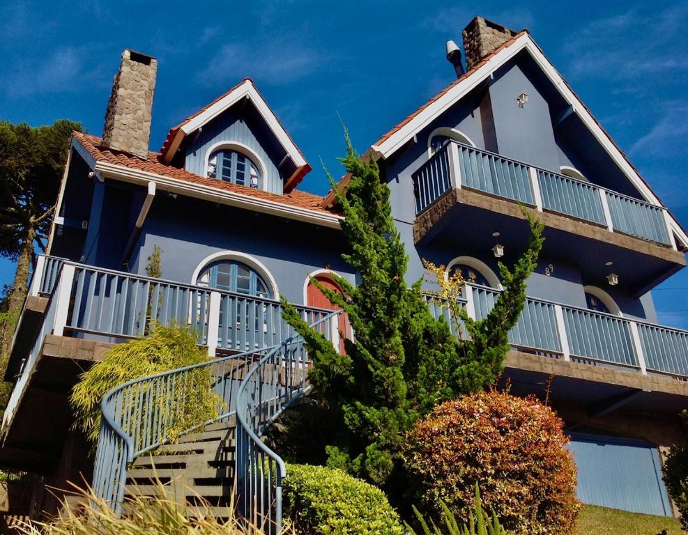 una casa azul y blanca con escaleras en la parte delantera en Chalé Alto da Serra - Pousada & Wellness Spa, en São Joaquim