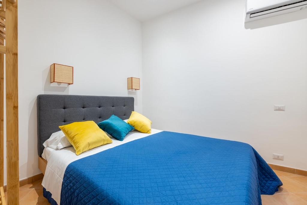 Un dormitorio con una cama azul con almohadas amarillas y azules en Elle Cavour Apartment en Roma