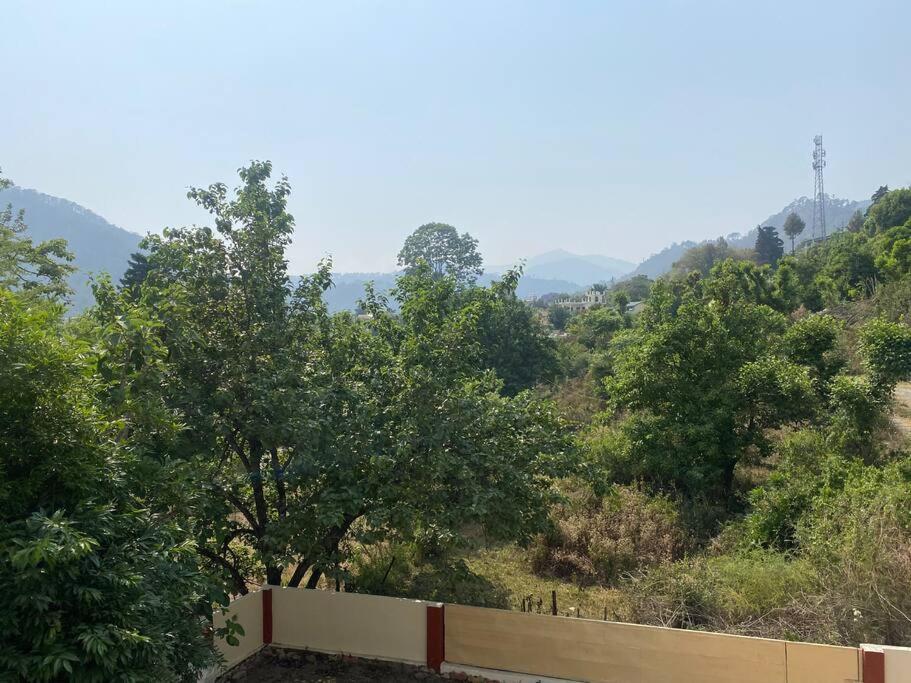 BhowāliにあるHighway Orchardの木々と柵のある丘の景色