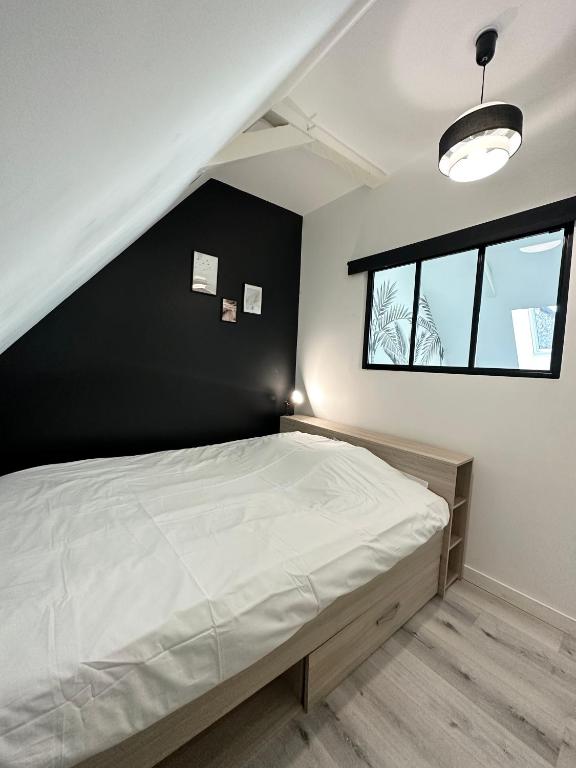 a bedroom with a bed with a black wall at L&#39;ENSOLEILLÉ - Classé 2 étoiles - Nay centre - Appartement in Nay