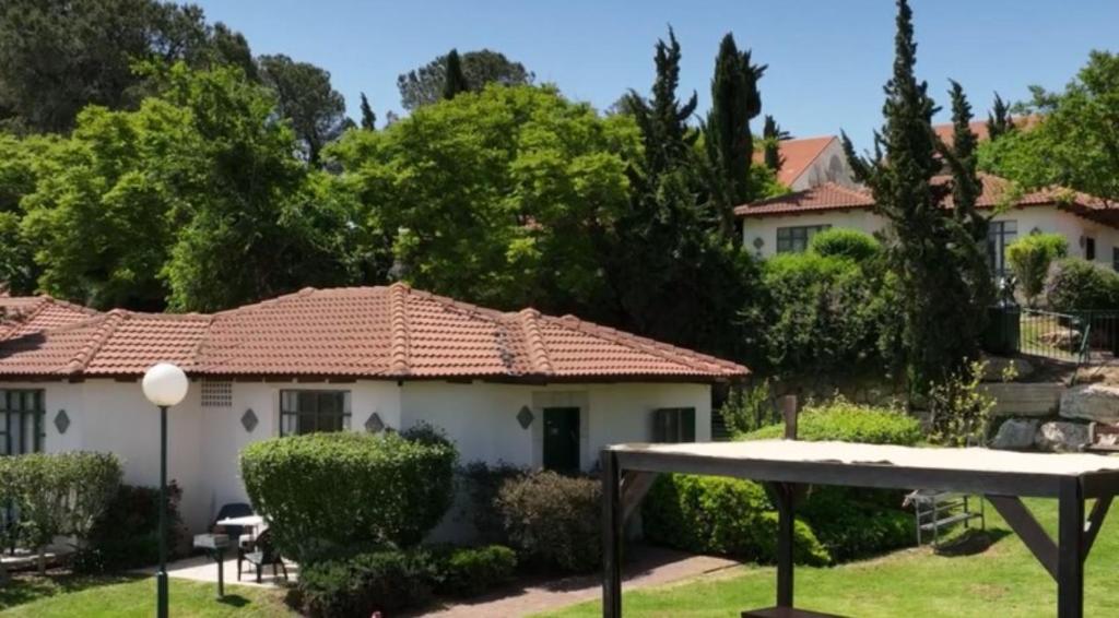 une maison blanche avec un toit rouge dans l'établissement Shoresh Green Hills, à Shoresh