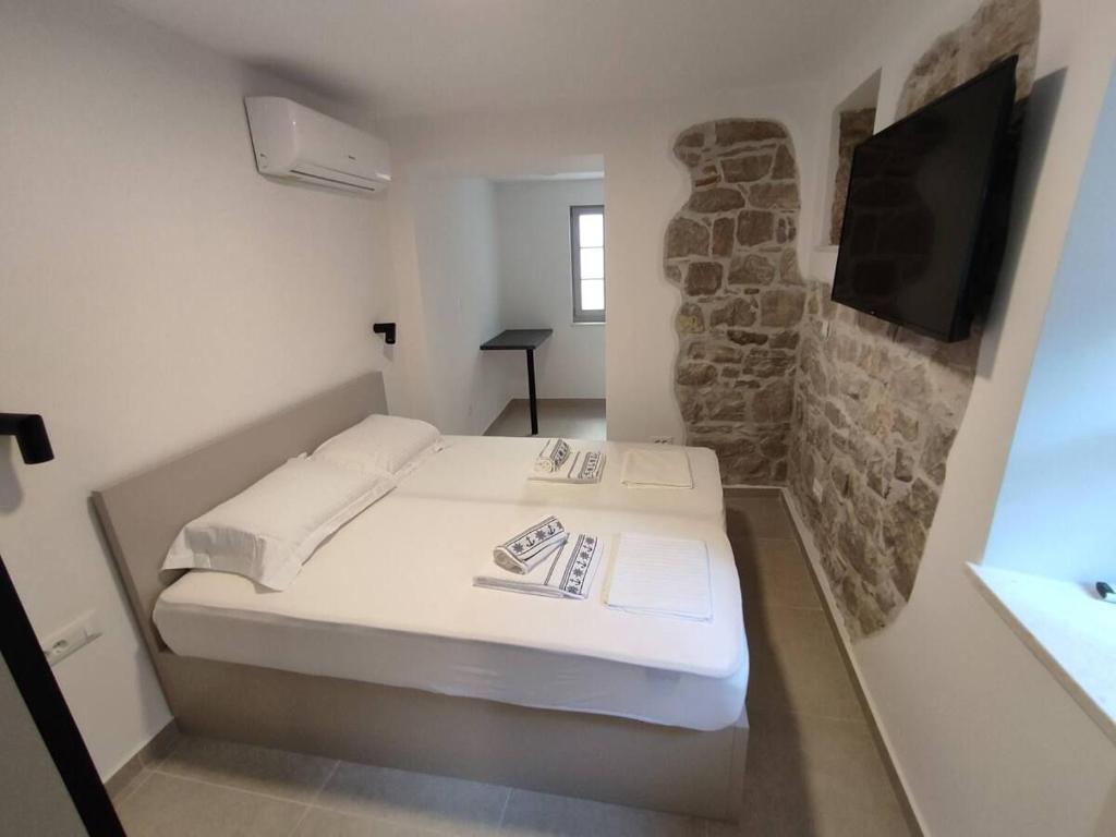 a small bedroom with a bed and a tv at The center of Split, renovated stone house in Split