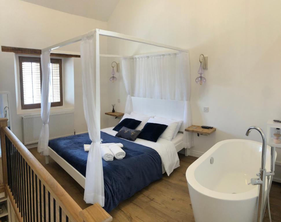 a bedroom with a bed and a bath tub at Honeybee Cottage, Waddington in Waddington