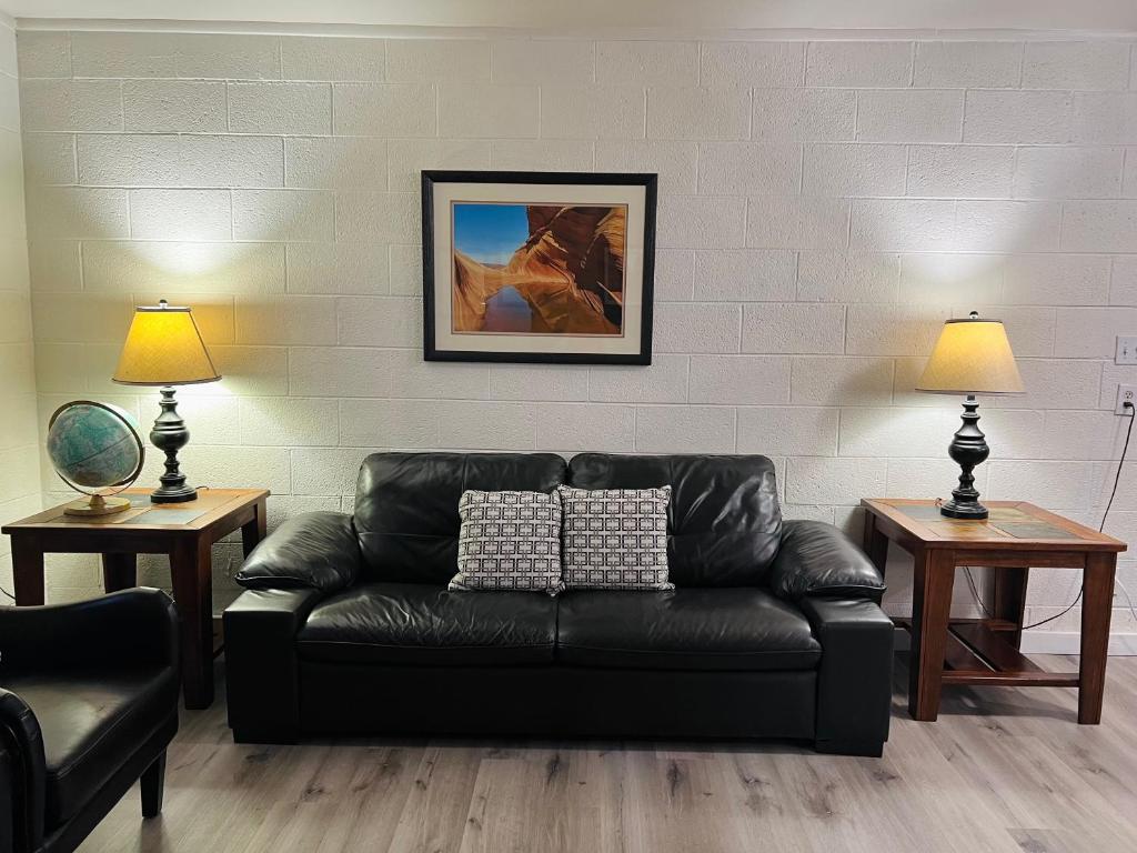 a black leather couch in a living room with two lamps at Lake Powell Motel & Apartments in Page