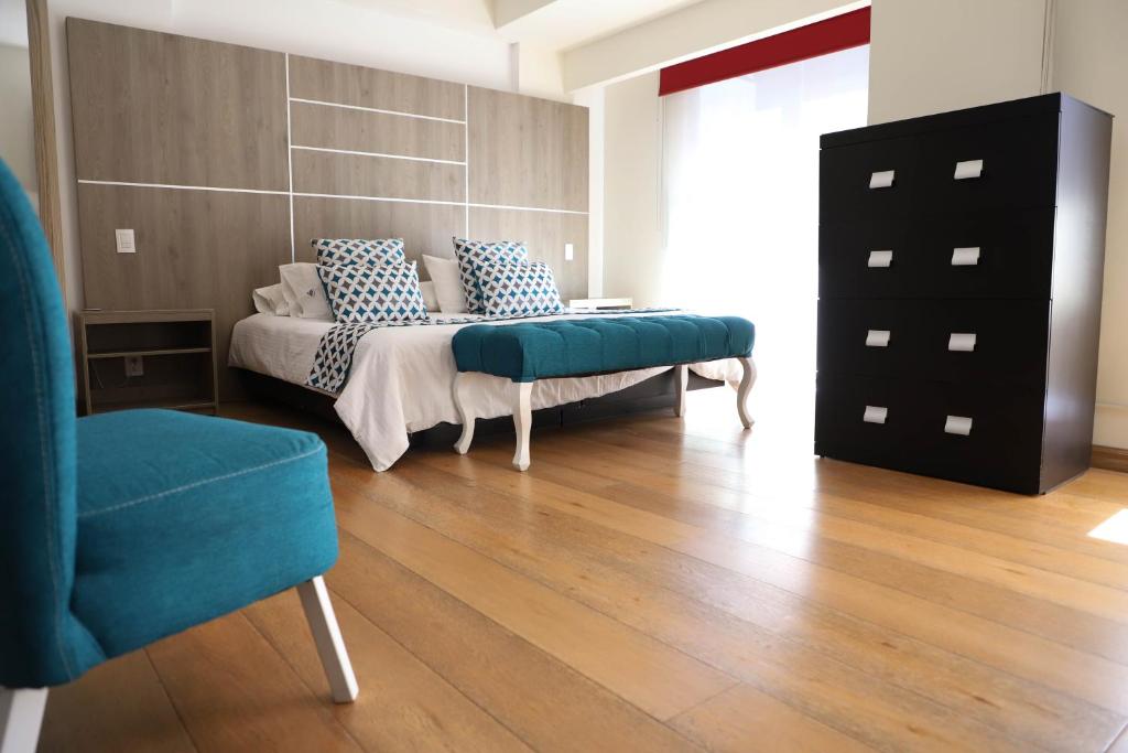 een kamer met een bed, een stoel en een dressoir bij Capital Luxury Apartments & Offices in Mexico-Stad