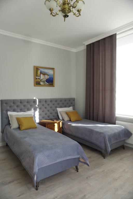 1 dormitorio con 2 camas y lámpara de araña en Home Apart, en Astana