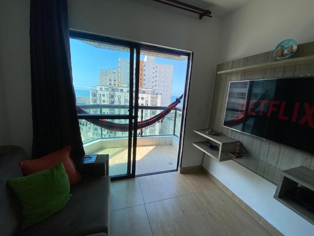 un soggiorno con una grande porta a vetri che conduce a un balcone di Apartamento cidade ocian Praia Grande a Praia Grande