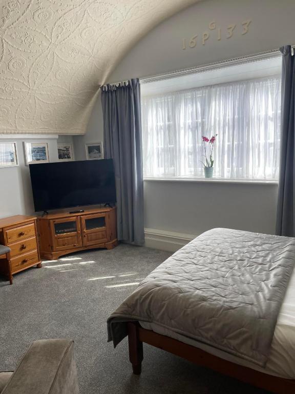 um quarto com uma cama e uma televisão de ecrã plano em The Lugger Fowey em Fowey