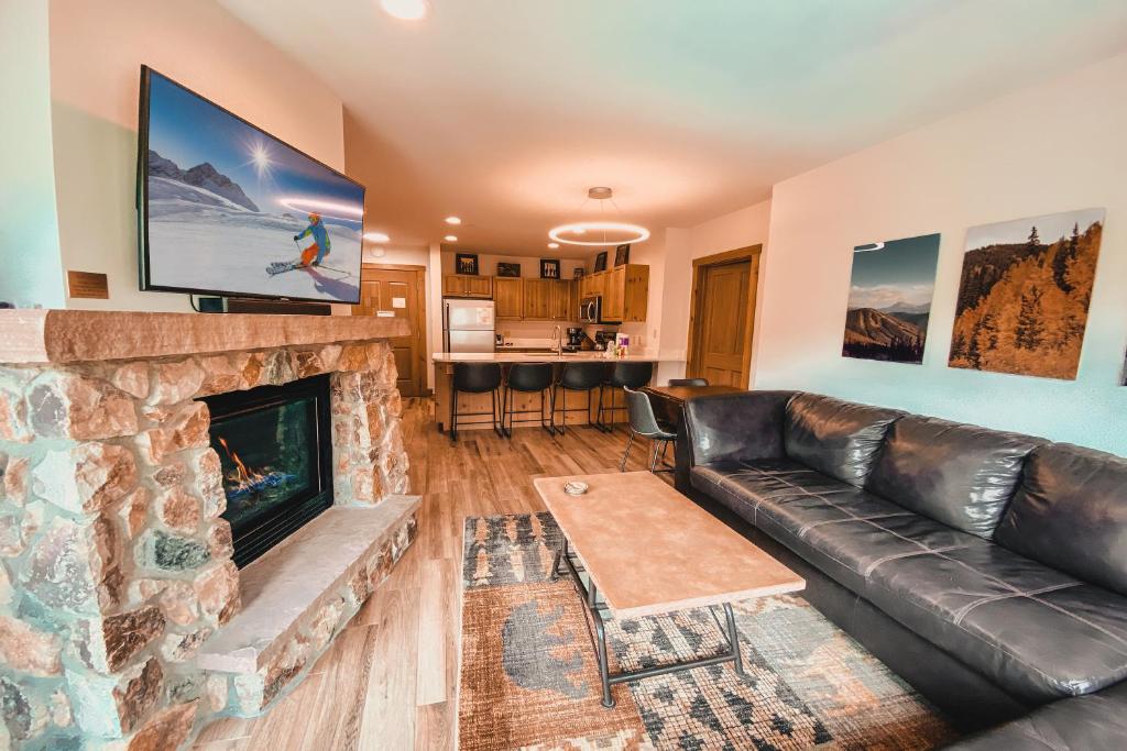a living room with a leather couch and a fireplace at Expedition Station 8607 in Keystone