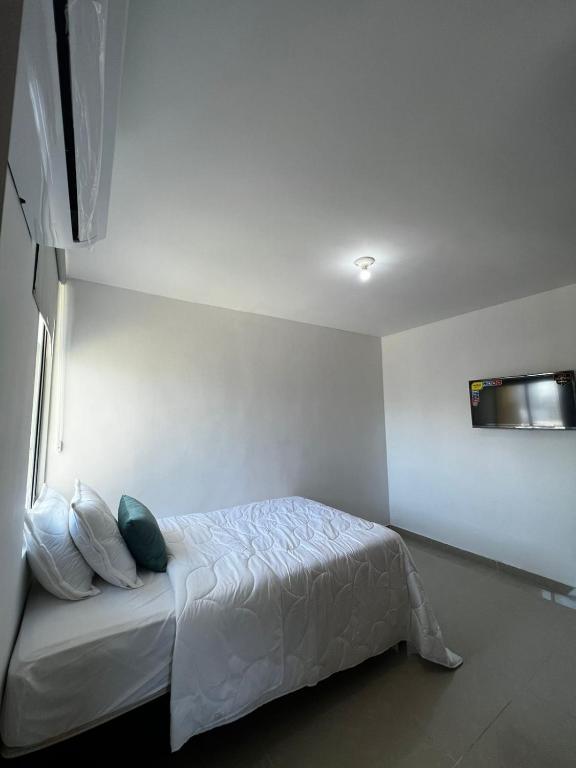 um quarto com uma cama branca com almofadas em apartamento barranquilla villa campestre! em Puerto Colombia