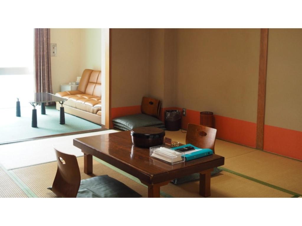 ein Wohnzimmer mit einem Tisch und einem Sofa in der Unterkunft Kokuminshukusha Shodoshima - Vacation STAY 59358v in Ikeda