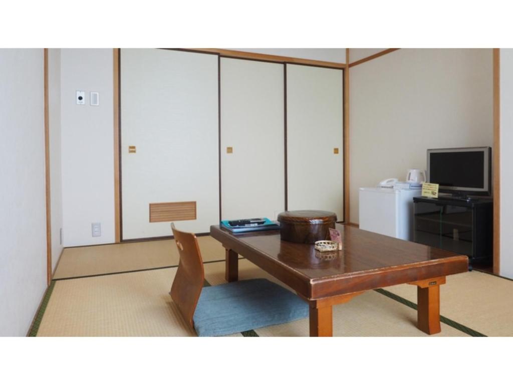 un soggiorno con tavolo in legno e TV di Kokuminshukusha Shodoshima - Vacation STAY 59346v a Ikeda
