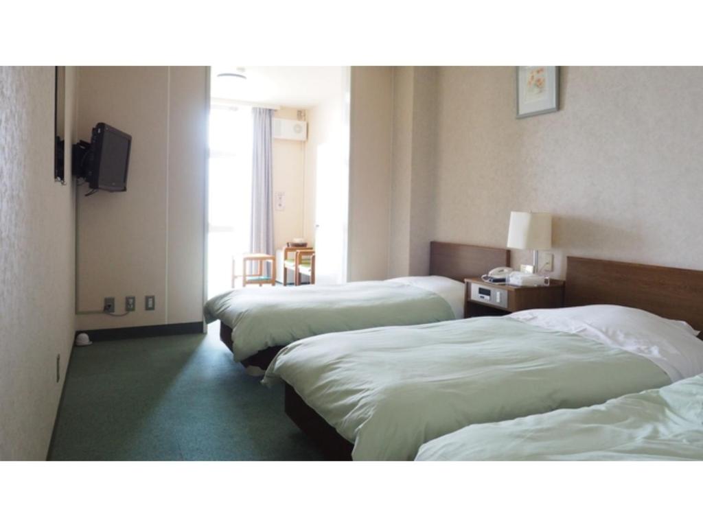 um quarto de hotel com três camas e uma televisão em Kokuminshukusha Shodoshima - Vacation STAY 59365v em Ikeda