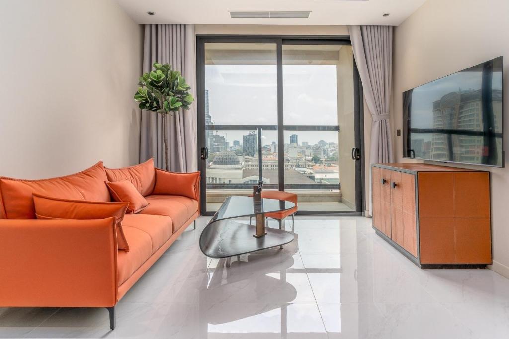 胡志明市的住宿－The Rixx Spectacular Apartment @ Opera House-Hyatt，客厅配有橙色沙发和电视