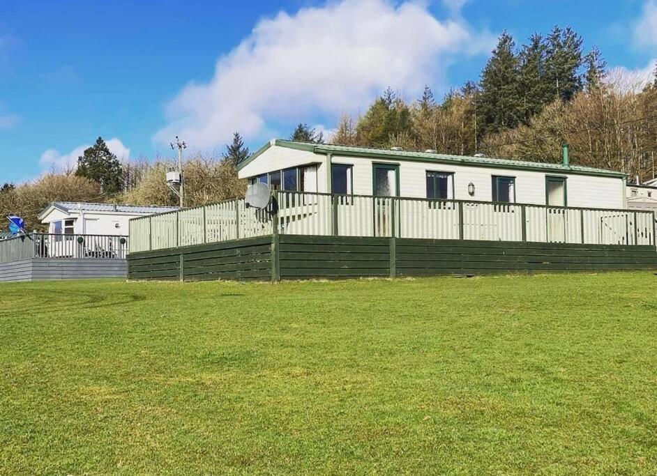 a white house with a fence and a grass field at No29 at Three Lochs Holiday Park in Balminnoch