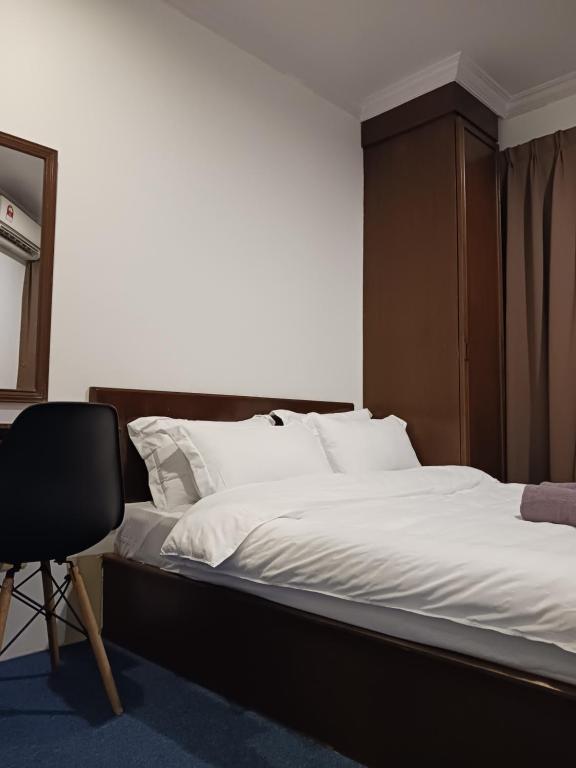 a bedroom with a bed with a black headboard and a chair at AeCOTEL in Sandakan