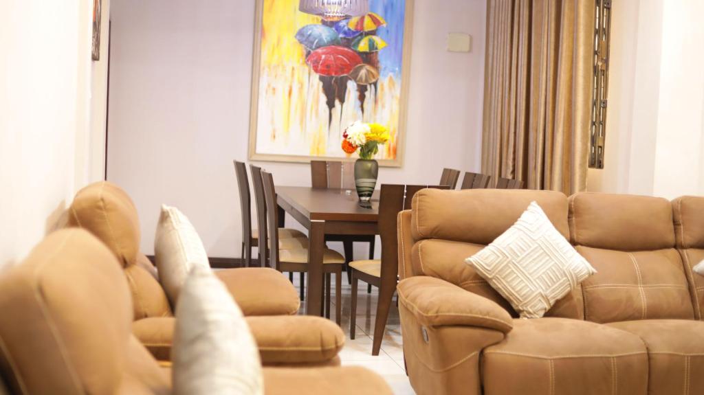 sala de estar con sofá y mesa con sillas en Jeffston Court Apartments en Accra