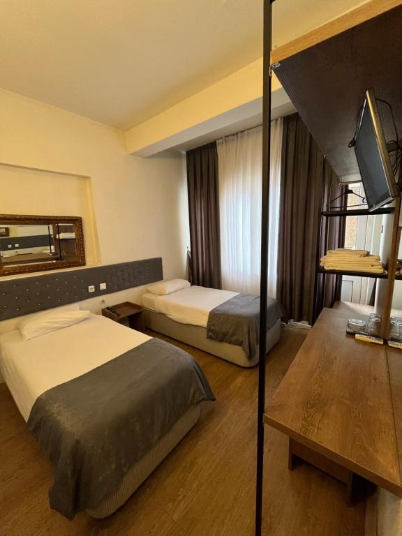 a hotel room with two beds and a tv at Hotel Ünlü in Aydın