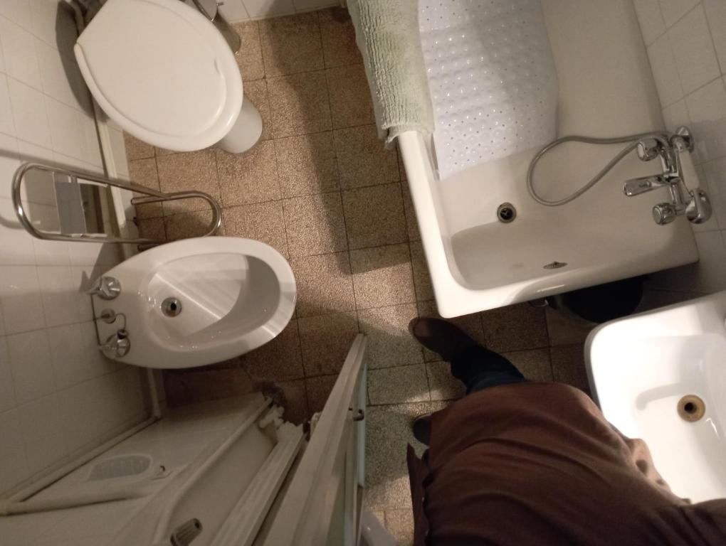 a person standing in a bathroom with a sink and a toilet at Casa San Carlo Affittacamere Foligno in Foligno